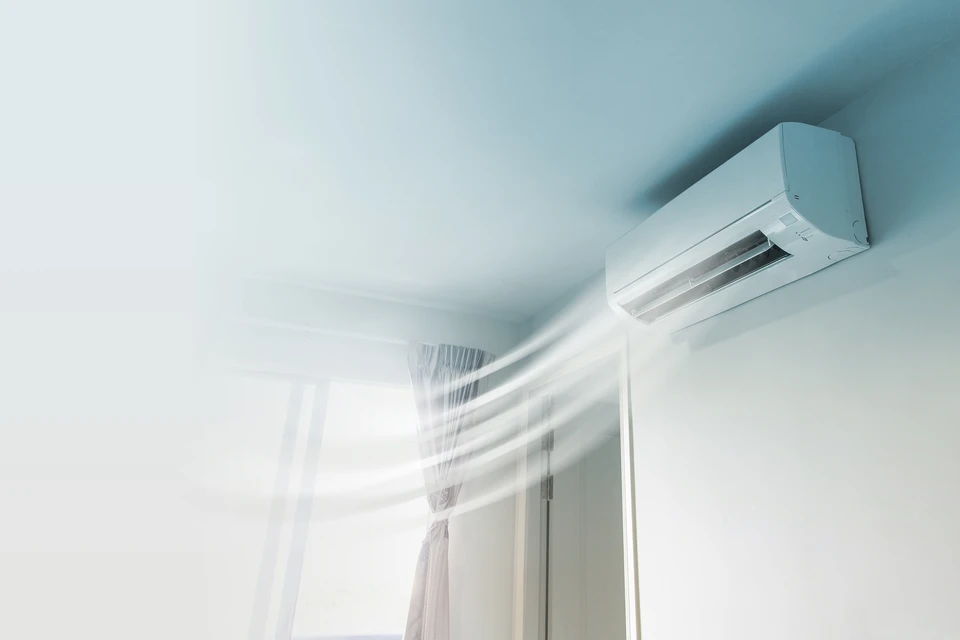 Intérieur moderne avec climatiseur mural blanc en fonctionnement, flux d'air visible soufflant vers des rideaux blancs flottants près d'une fenêtre