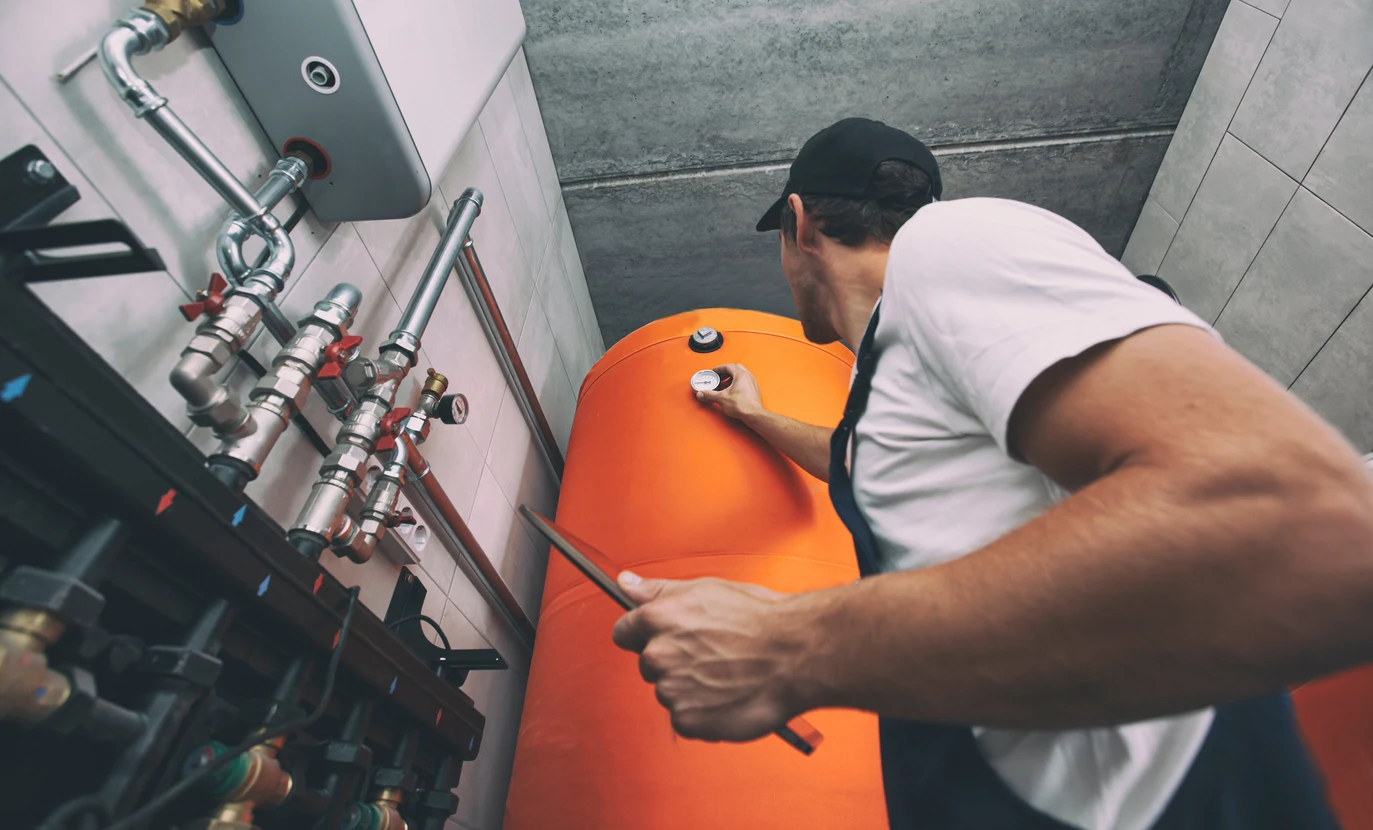 Un technicien en tenue de travail effectue la maintenance d'un système de chauffage dans un local technique moderne