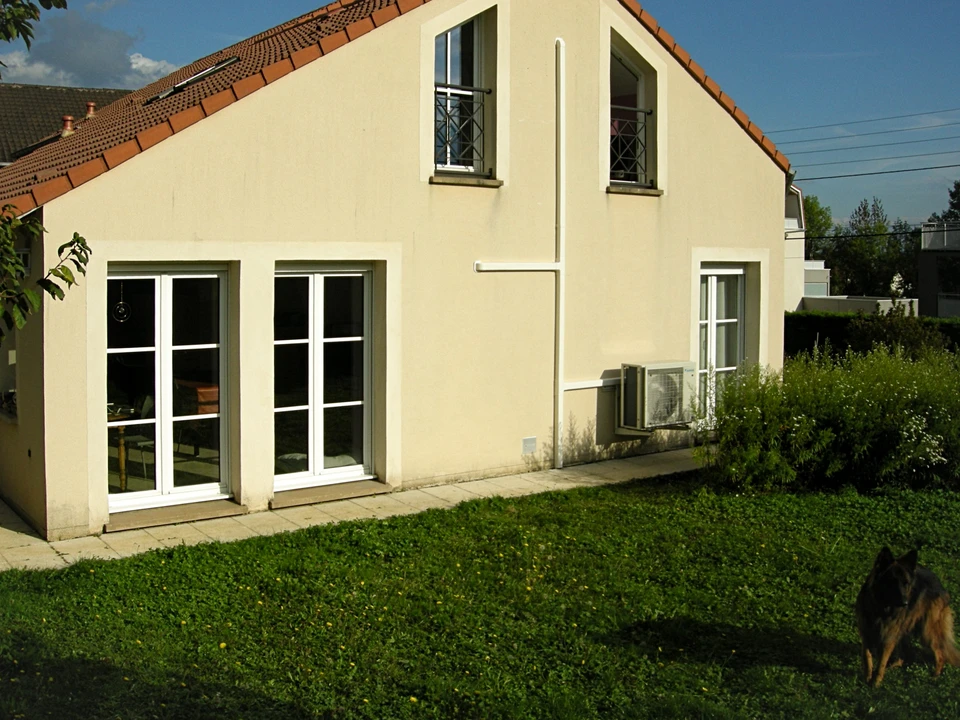 Scène extérieure résidentielle avec maison moderne à toit d'ardoise et système géothermique enterré dans jardin gazonné